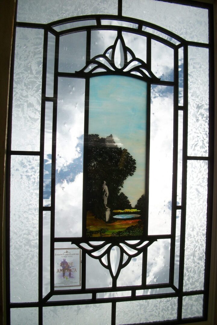 Artistic stained glass window featuring a central panel with a figure in a landscape, surrounded by decorative frosted glass with a sky view.